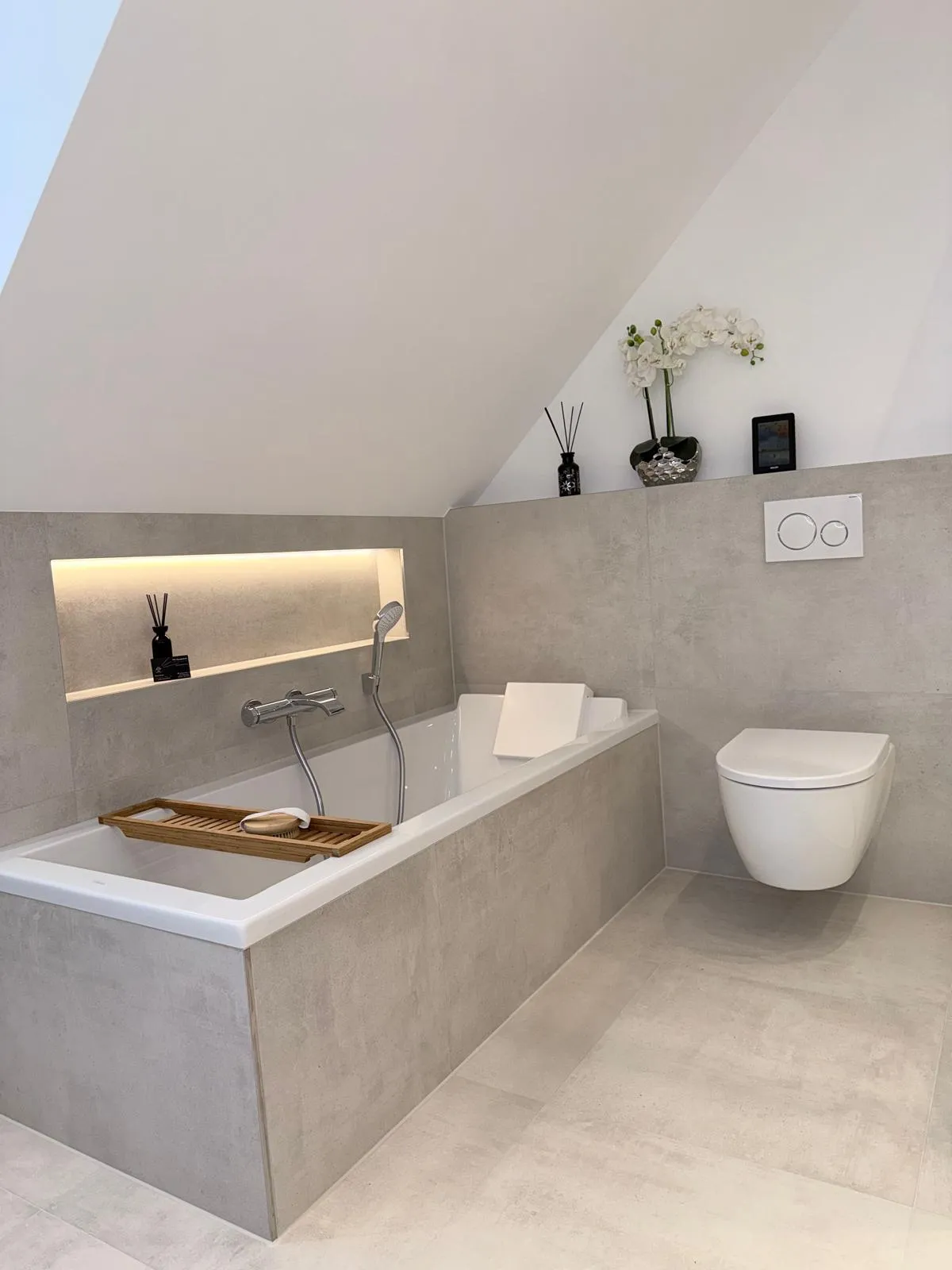 Fertiges Dachgeschossbad mit Badewanne, beleuchteter Nische und wandhängendem WC