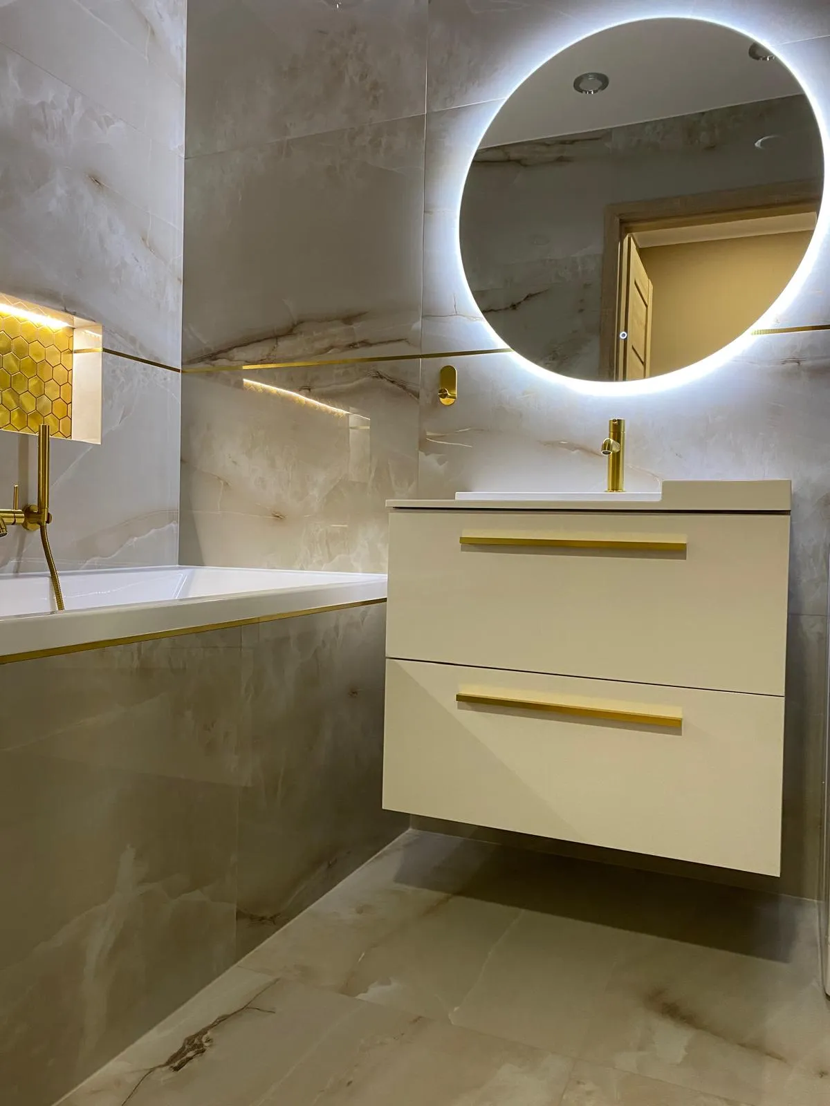 Fertiges Bad mit goldenen Armaturen und rundem LED-Spiegel