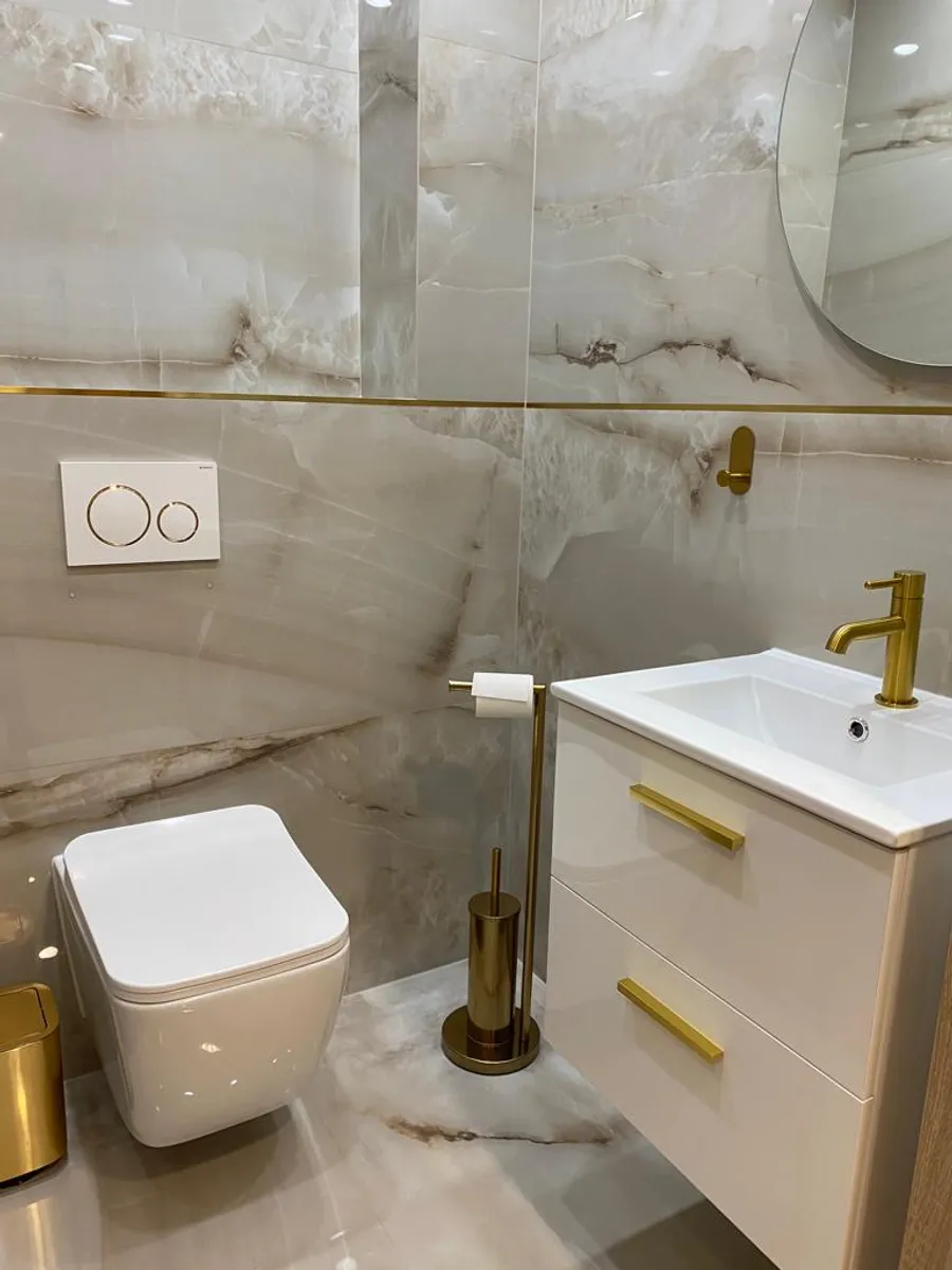 Gäste-WC in Onyx-Optik mit wandhängendem WC, Waschtisch und goldenen Armaturen