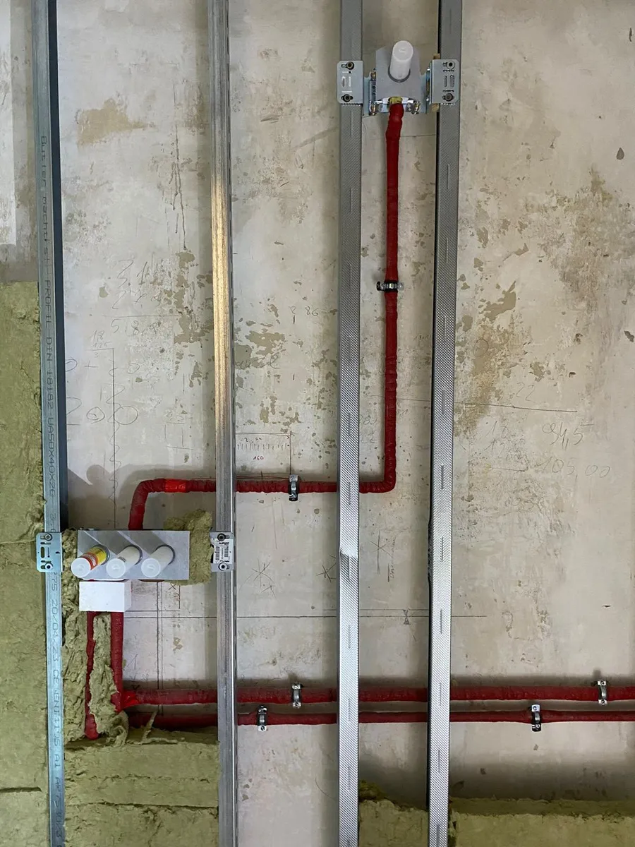 Rote Sanitärleitungen an einer Metallständerwand